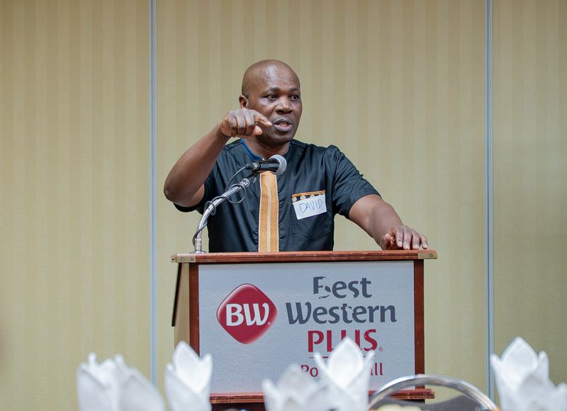 A guest speaker gestures to the audience while speaking at the lectern