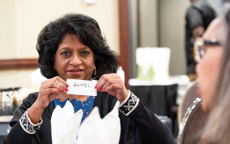A participant smiles as she holds up her name tag