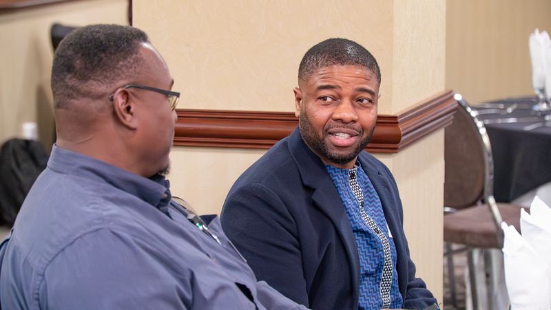 Two men smile and talk at their table